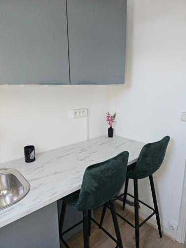 a kitchen with a counter and two green chairs at Chambre privée à 50 m de la plage- Parking privé, salle de bain et cuisine commune in Le Portel