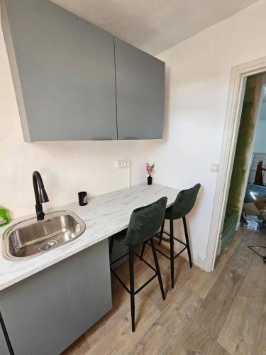 a kitchen with a sink and two chairs at Chambre privée à 50 m de la plage- Parking privé, salle de bain et cuisine commune in Le Portel