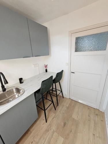 a kitchen with a table and two chairs and a door at Chambre privée à 50 m de la plage- Parking privé, salle de bain et cuisine commune in Le Portel