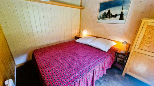 a small bedroom with a bed with a red blanket at Chalet l Houtot in Evolène