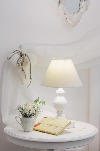 a table with a lamp and a book and a vase of flowers at Il Cuore delle Apuane in Antona