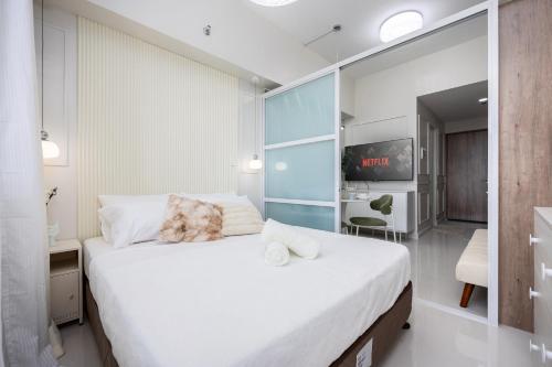 a bedroom with a large white bed with a mirror at Primeworld District Condo - Near Mactan Airport in Lapu Lapu City