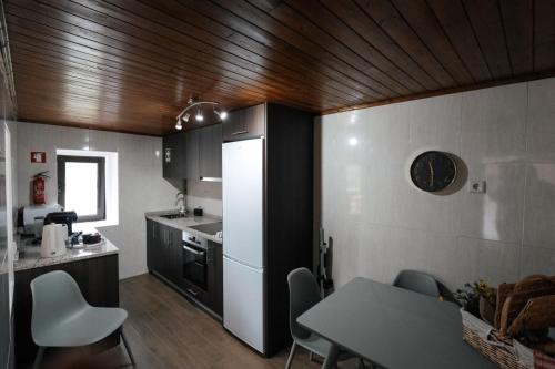 a kitchen with a table and a refrigerator and a table and chairs at Refúgio do Barqueiro - Douro in Mesão Frio