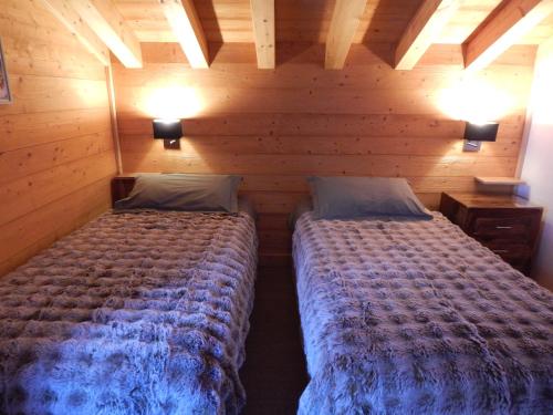 a bedroom with two beds in a wooden room at Chalet LE VAL NESS in La Côte dʼArbroz