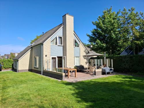 a house with a patio with a table and chairs at Villapark Kamperfoelie 33 in De Koog