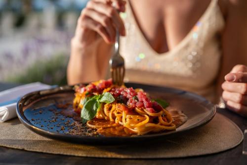 a person eating a plate of pasta with a fork at Resort La Battigia Beach & Spa in Alcamo Marina