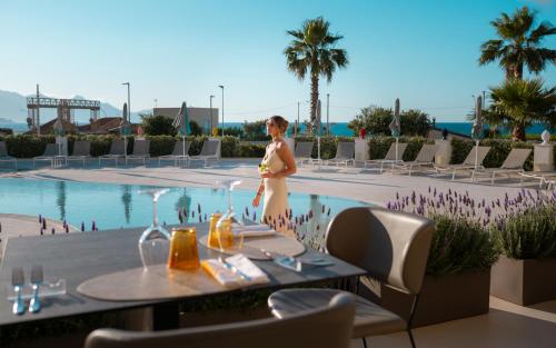 a woman standing in front of a pool at a resort at Resort La Battigia Beach & Spa in Alcamo Marina