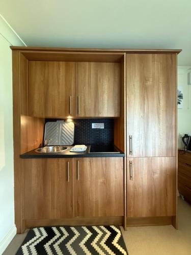 a kitchen with wooden cabinets and a microwave at Bagshaw Lodge in Bakewell