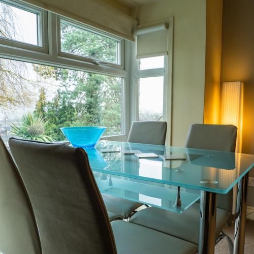 a glass table with chairs in front of a window at Bagshaw Lodge in Bakewell