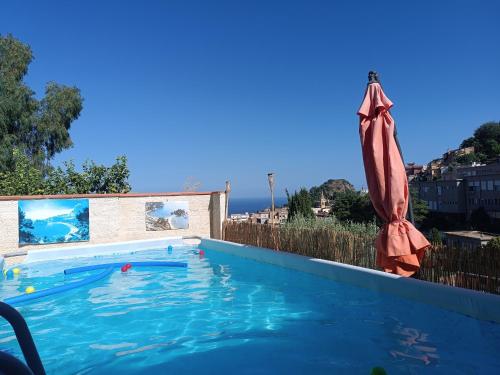 a large swimming pool with an umbrella and a swimming pool at Le Grand Soleil Apartments in Taormina