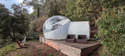 a dome tent with two chairs on a wooden deck at Logements insolites du Domaine de la Tuilière in Carnoules