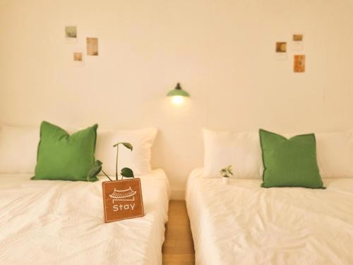 two beds with green pillows with a sign that says stay at N-Stay#CozySpace#Pyeongtaek Station#Bus Terminal#K6 Humphreys#Samsung in Pyeongtaek