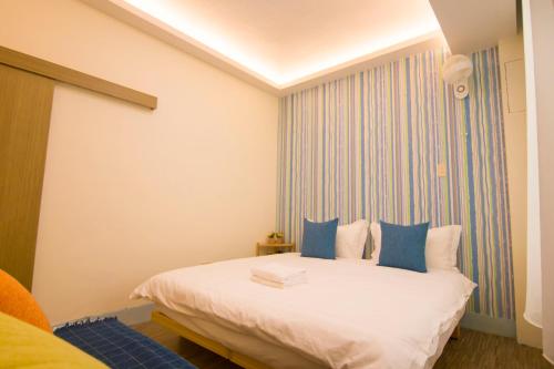 a bedroom with a white bed with blue pillows at One Heart Inn in Tainan