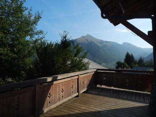 a wooden deck with mountains in the background at Chalet LE VAL NESS in La Côte dʼArbroz