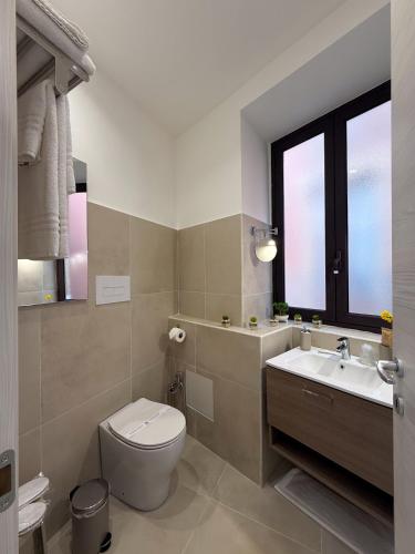 a bathroom with a toilet and a sink and a window at Town House 54 in Catania