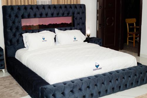 a large bed with a black headboard and white sheets at Sapphire Guest House and Event Centre in Trofwi