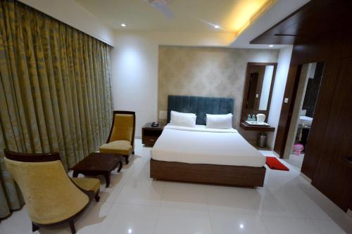 a hotel room with a bed and two chairs at Hotel City Heart Shirdi in Shirdi