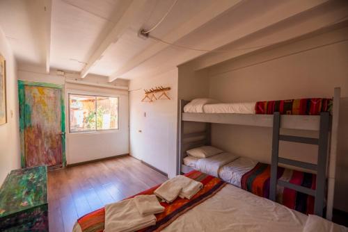 a room with two bunk beds and a window at Hostal Copart in San Pedro de Atacama