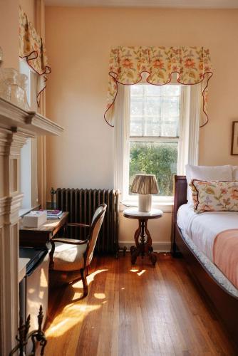 a bedroom with a bed and a desk and a window at Ironclad Inn and Bourbon Room in Fredericksburg