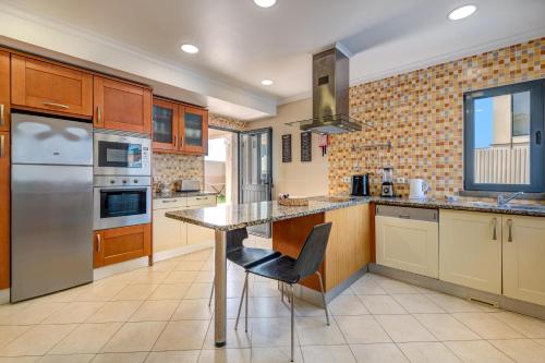 a kitchen with wooden cabinets and stainless steel appliances at Villa Ruana - 5 bedrooms on Suite- Free out door Hot Jacuzzi - By Bedzy in Albufeira