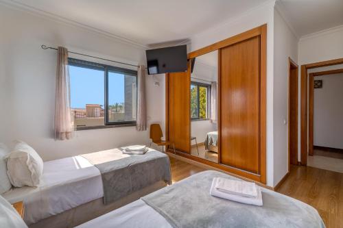 a bedroom with two beds and a large window at Villa Ruana - 5 bedrooms on Suite- Free out door Hot Jacuzzi - By Bedzy in Albufeira