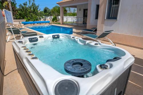 a jacuzzi tub with chairs and a pool at Villa Ruana - 5 bedrooms on Suite- Free out door Hot Jacuzzi - By Bedzy in Albufeira