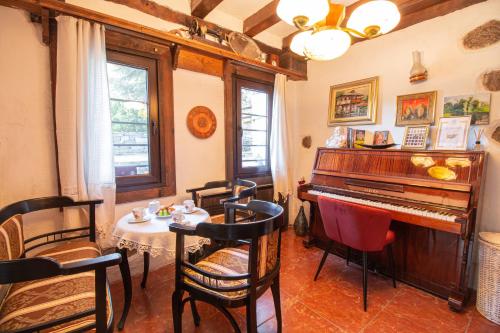 a living room with a piano and a table and chairs at Дедовата Къща in Dedovo