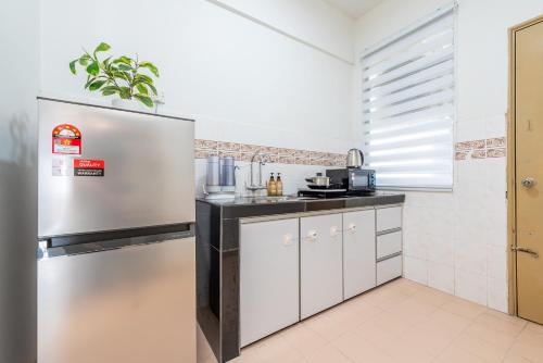 a kitchen with white cabinets and a stainless steel refrigerator at PortDickson Cozy Muji Home 10Pax3BR 1min to beach in Port Dickson