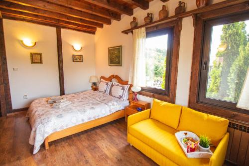 a bedroom with a bed and a yellow couch at Дедовата Къща in Dedovo