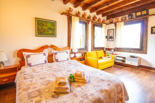 a bedroom with a large bed and a yellow chair at Дедовата Къща in Dedovo