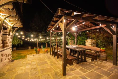 a wooden pergola with a wooden table and benches at Дедовата Къща in Dedovo
