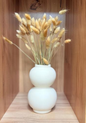 a white vase with flowers in it on a table at DendroBak GuestHouse in Stepʼanavan