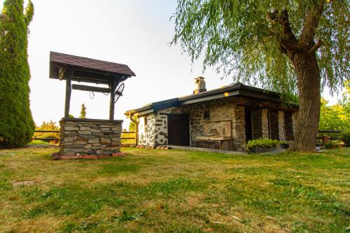 a small stone building with a gazebo next to a tree at Дедовата Къща in Dedovo