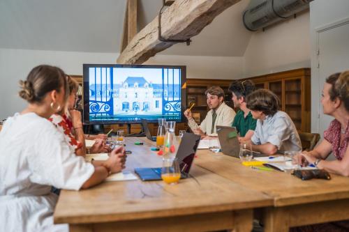 a group of people sitting around a table with a television at Le Domaine de Richebourg - Pierres d'Histoire in Richebourg
