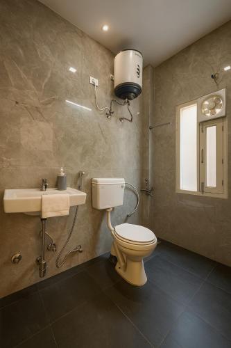 a bathroom with a toilet and a sink at The White Scent-Near Noida Sector34 Metro in Noida
