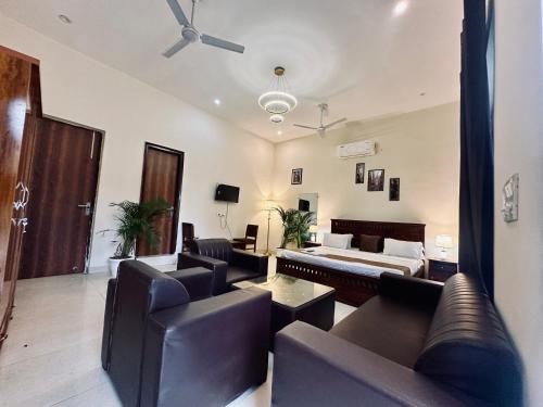 a living room with leather furniture and a ceiling fan at The White Scent-Near Noida Sector34 Metro in Noida