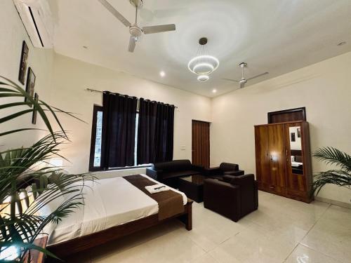a bedroom with a bed and a chair and a couch at The White Scent-Near Noida Sector34 Metro in Noida