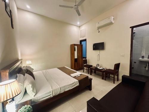a bedroom with a bed and a desk in a room at The White Scent-Near Noida Sector34 Metro in Noida