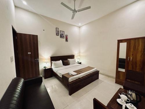 a bedroom with a bed and a leather couch at The White Scent-Near Noida Sector34 Metro in Noida