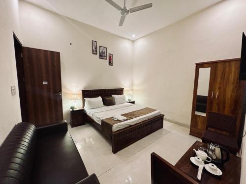 a bedroom with a bed and a leather couch at The White Scent-Near Noida Sector34 Metro in Noida