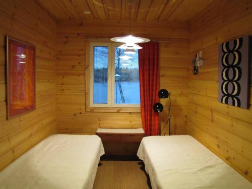 a log cabin with two beds and a window at Kaijonselän mökit Pyhitty in Vehmaskylä