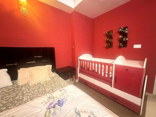 a bedroom with a crib and red walls at Three Bed Premium Apartment in Islamabad