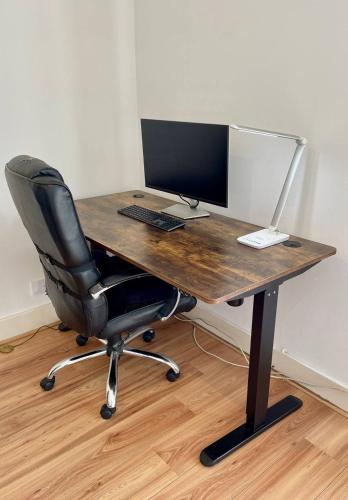 a wooden desk with a computer monitor and a chair at Chic Duplex w Rooftop Retreat in Dublin
