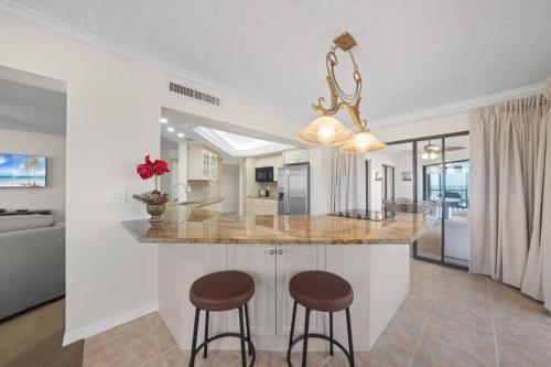 a kitchen with two bar stools and a counter top at Pointe Santo A24 condo in Sanibel