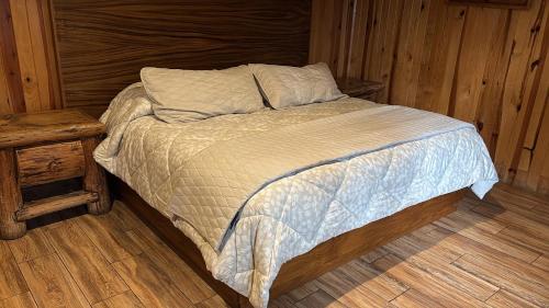 a bed in a wooden bedroom with a wooden floor at Cabaña DNellys Rosa con cancha de basquetbol in Mazamitla