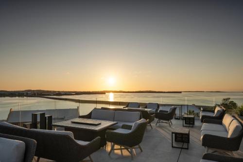 a patio with chairs and tables and the sunset at Grotto Bay Beach Resort in Tuckerʼs Town