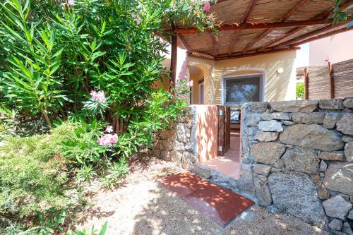 a house with a stone wall and a fence at Calarossa Beach House in Isola Rossa