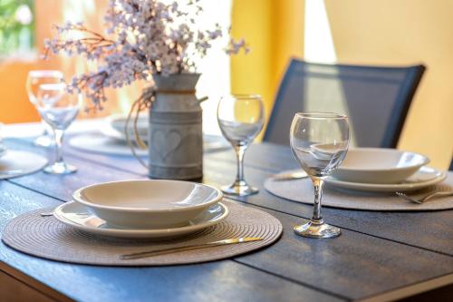 a wooden table with plates and wine glasses on it at Calarossa Beach House in Isola Rossa