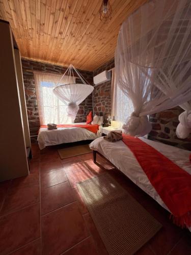a bedroom with two beds and a stone wall at Tsauchab River Camp in Sesriem