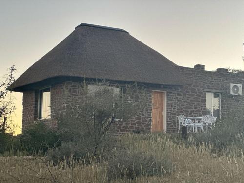 a brick house with a thatched roof with a table at Tsauchab River Camp in Sesriem